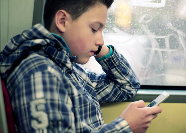 A boy using the phone on a bus