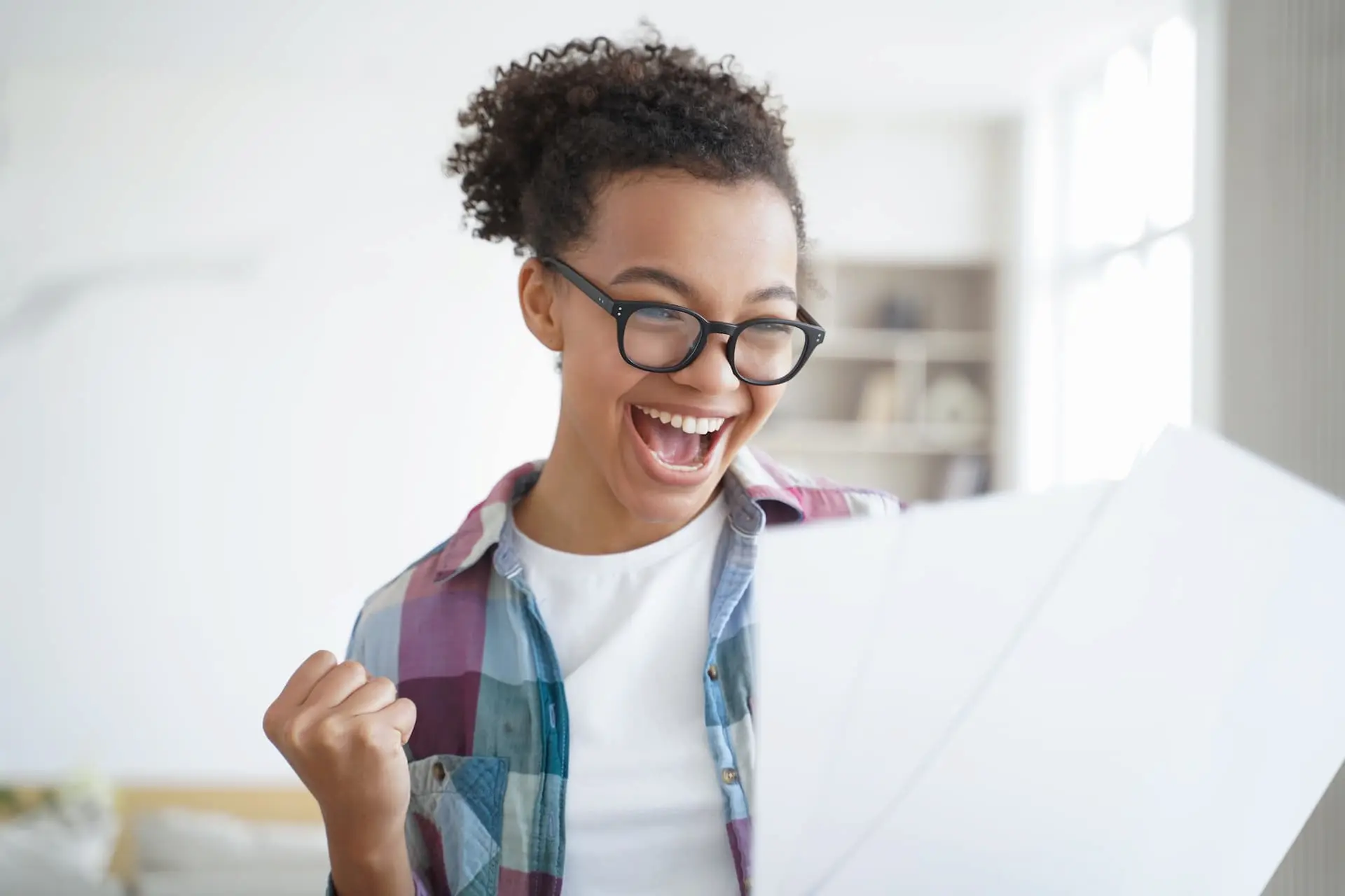 A female student looking at her grades anc cheering with her first pumped high.