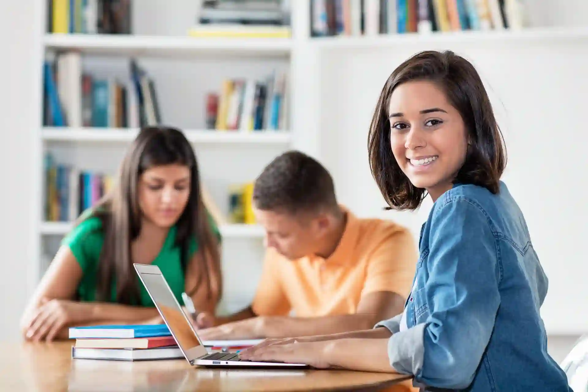 A student looking to the side and smiling while working at a laptop.