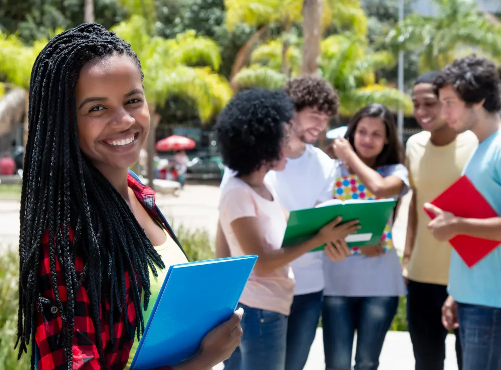 A student standing in front of a group of students, smiling.