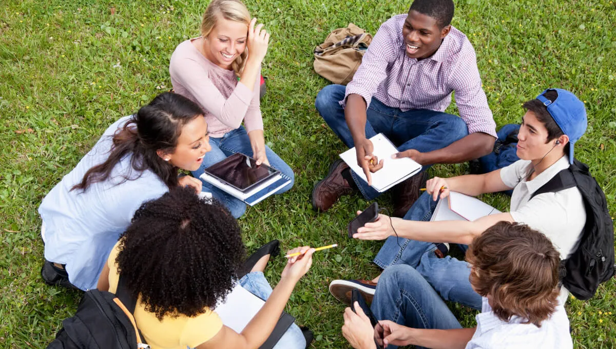 A student standing in front of a group of students, smiling.
