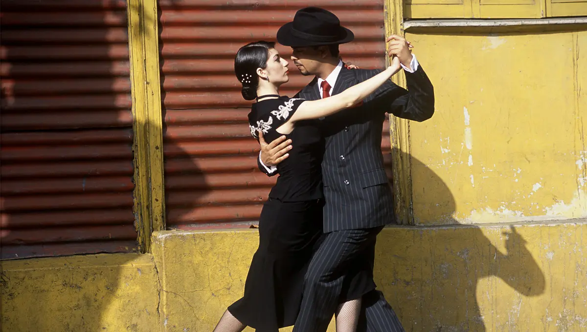 A man and woman dancing beside a building.