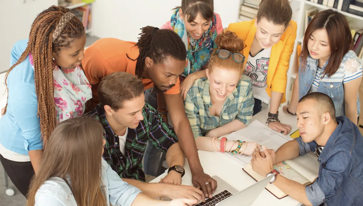 A group of students studying together on a grassy field.