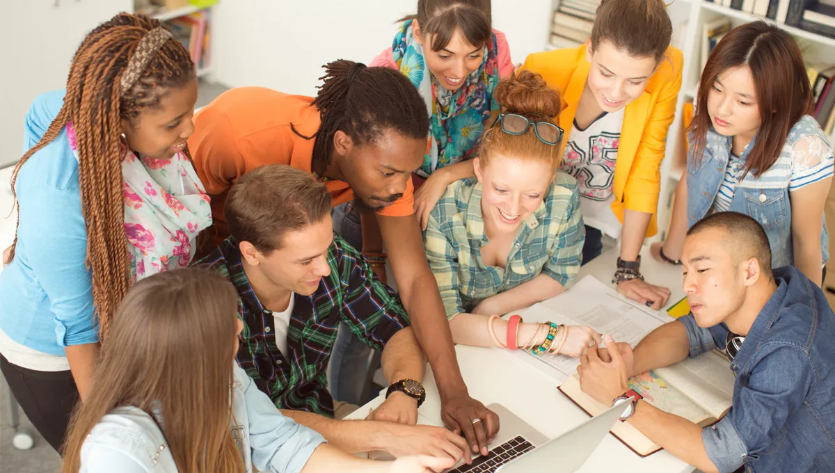 A group of students studying together on a grassy field.