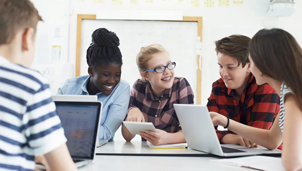 A group of students smiling using the supersite on different devices.