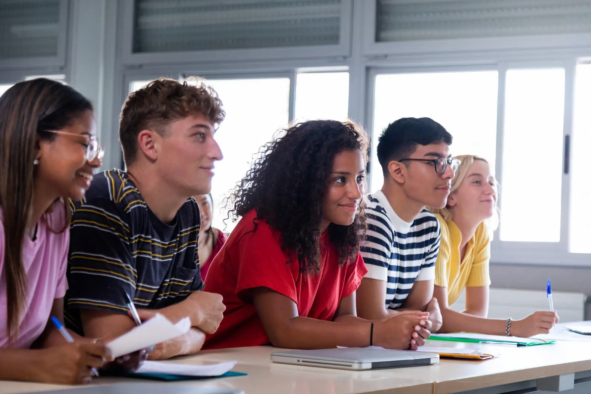 A group of students sitting and smiling while looking at the teacher.